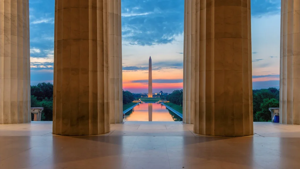 Washington Monument and Reflecting Pool at sunset, seen through the columns of the Lincoln Memorial in Washington, D.C.